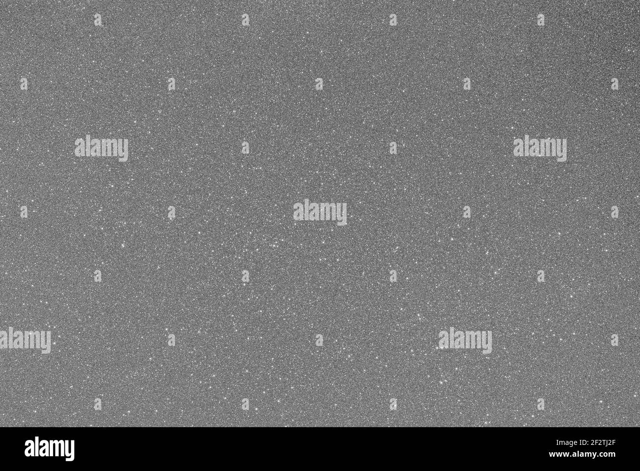 Des paillettes gris argenté fines recouvrent une surface texturée, créant un fond abstrait uniformément scintillant avec espace libre pour la mise en page. Banque D'Images