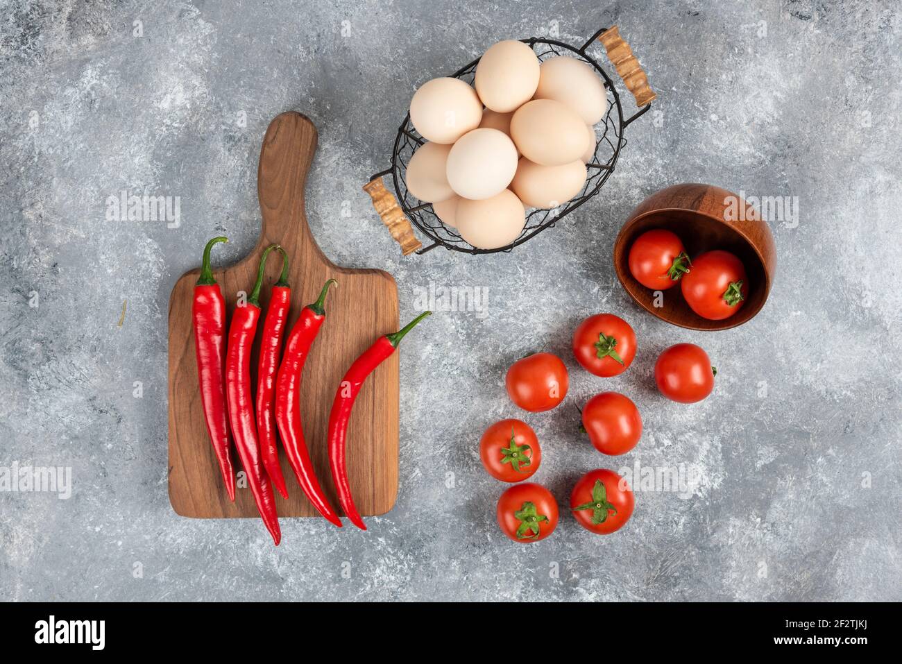 Panier en osier composé d'œufs biologiques crus et de légumes frais arrière-plan en marbre Banque D'Images