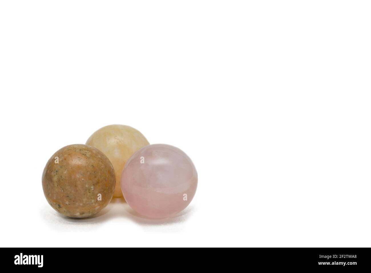 Trois boules en pierre naturelle. Quartz rose, calcide jaune et jasper. Isolé sur blanc, espace de copie. Banque D'Images