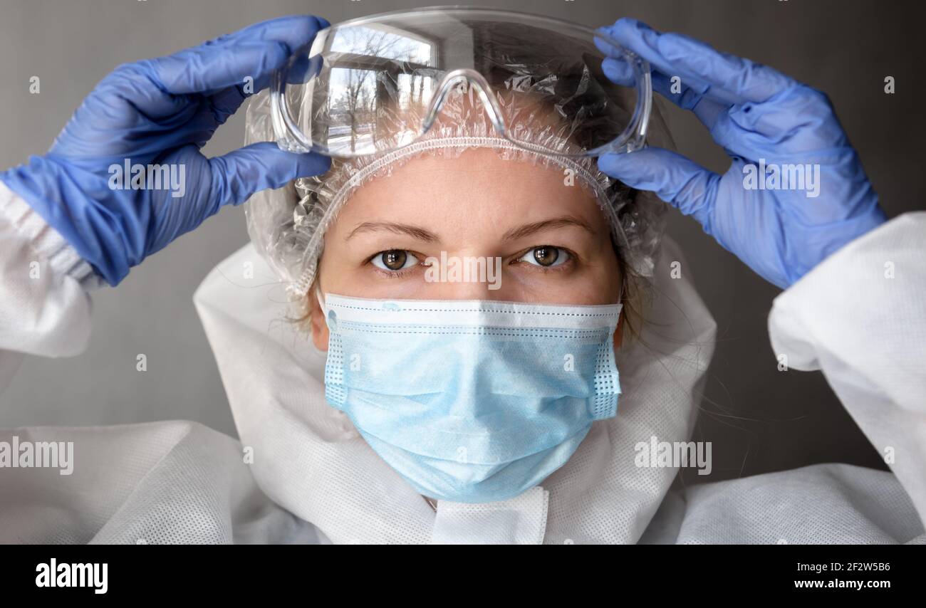 Médecin ou infirmière en costume d'EPI de COVID-19, portrait d'une femme médecin portant des lunettes de protection et un masque médical pour le visage en raison d'une pandémie de coronavirus. C Banque D'Images