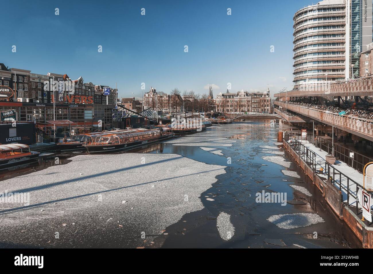 Amsterdam, pays-Bas, 12 février 2021 : le canal gelé Oosterdok dans le vieux centre d'Amsterdam avec le dû à COVID amarré des bateaux de visite sur le le Banque D'Images