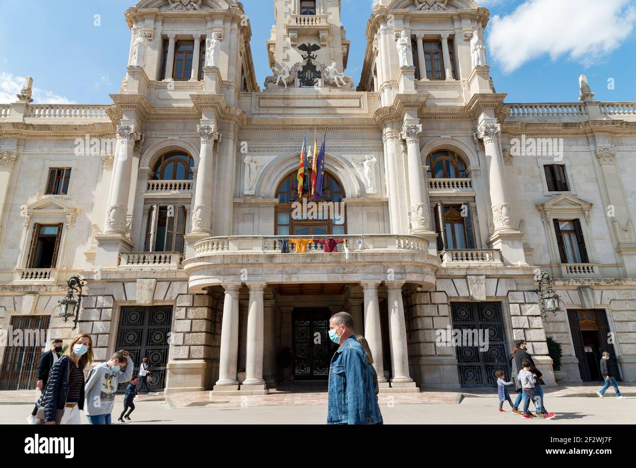 Valence, Espagne. 13 mars 2021. Les personnes portant un masque de visage marchent au-delà de l'hôtel de ville.tous les Fallas Act ont été suspendus de façon permanente en raison de la situation sanitaire causée par Covid19. Pour se souvenir de l'esprit des Fallas pendant la semaine suivante, un chaudron a été allumé comme un rappel sur la place de l'hôtel de ville de Valence. Crédit : SOPA Images Limited/Alamy Live News Banque D'Images