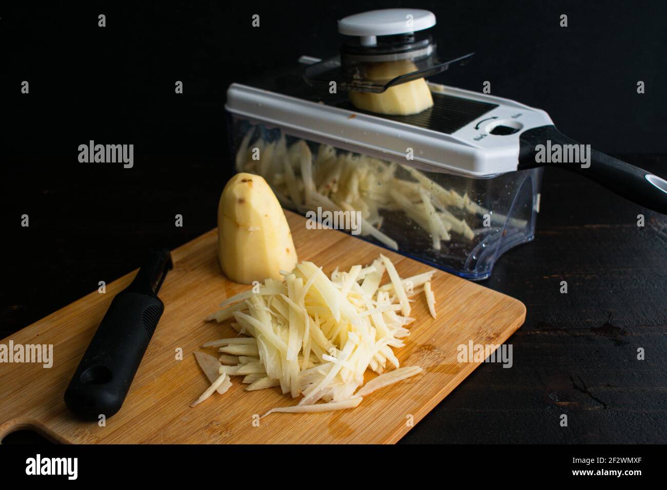 Déchiquetage de pommes de terre avec une mandoline : utilisation d'une mandoline pour julienne de pommes de terre russet Banque D'Images