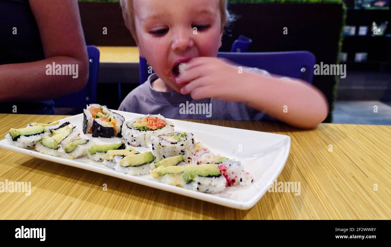 Un petit garçon (2 ans) manger des sushis dans un restaurant Banque D'Images
