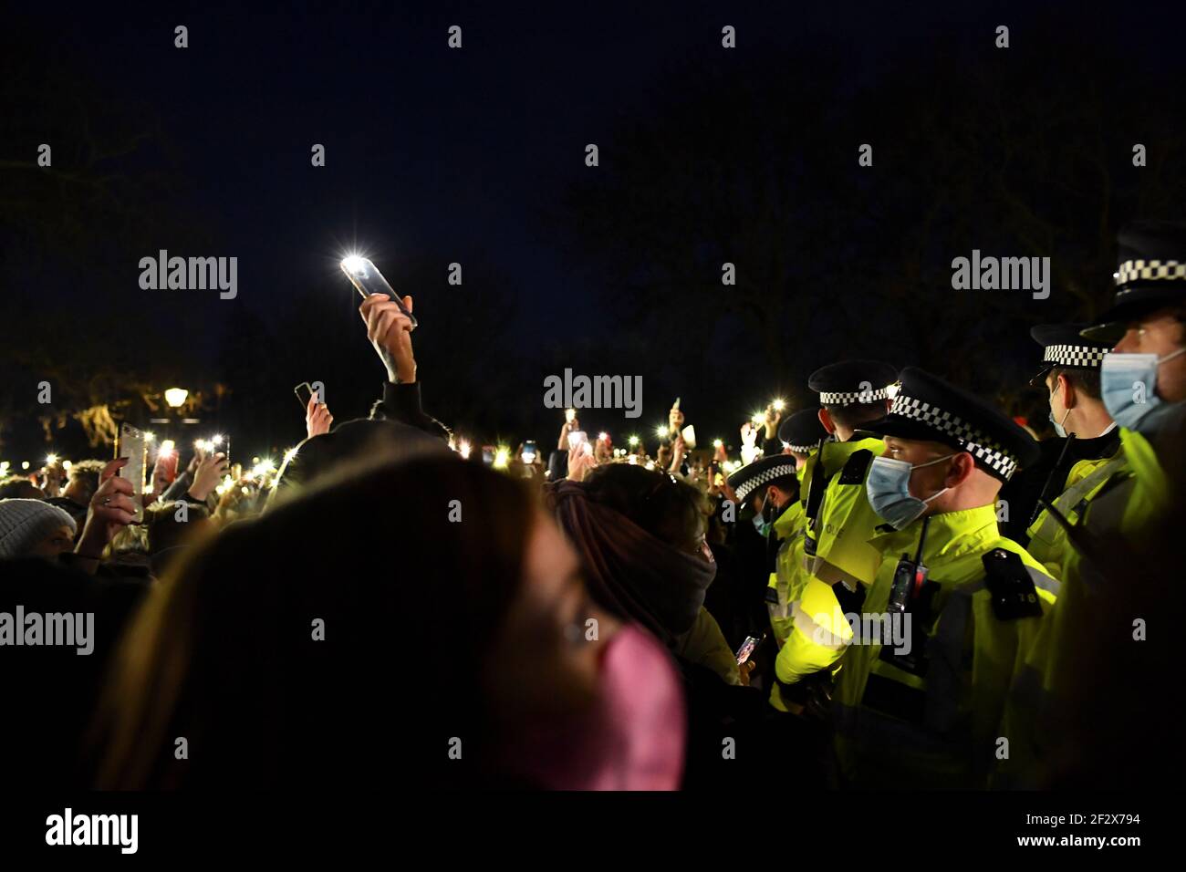 Les personnes en deuil se trouvent en face des membres de la police tandis que les gens se rassemblent sur un site commémoratif du Clapham Common Bandstand, à la suite de l'enlèvement et du meurtre de Sarah Everard, à Londres, en Grande-Bretagne, le 13 mars 2021. REUTERS/Dylan Martinez Banque D'Images