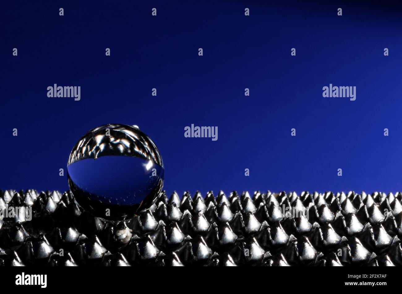 Sphère en verre sur fond bleu sur la surface moletée avec copie espace vue rapprochée Banque D'Images