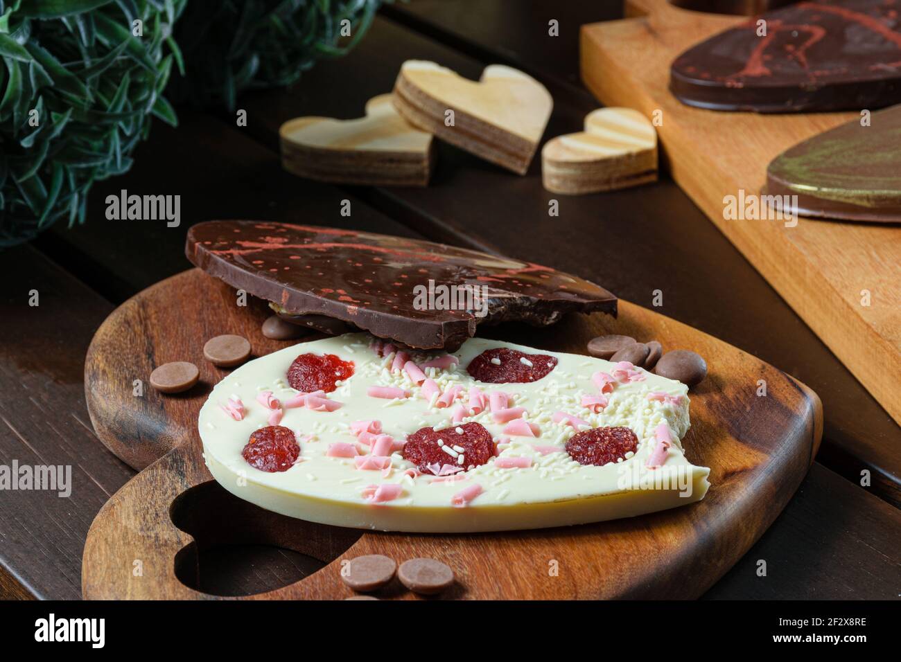 Gros plan de deux oeufs de Pâques piqués 2D (ovos de Pascoa) à côté des noix de Saint-Jacques au chocolat. Au premier plan, l'oeuf de chocolat blanc avec baie de goji. Banque D'Images