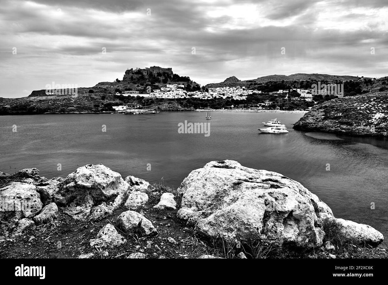 Une baie avec une côte rocheuse, la ville de Lindos et une forteresse médiévale sur l'île de Rhodes, monochrome Banque D'Images