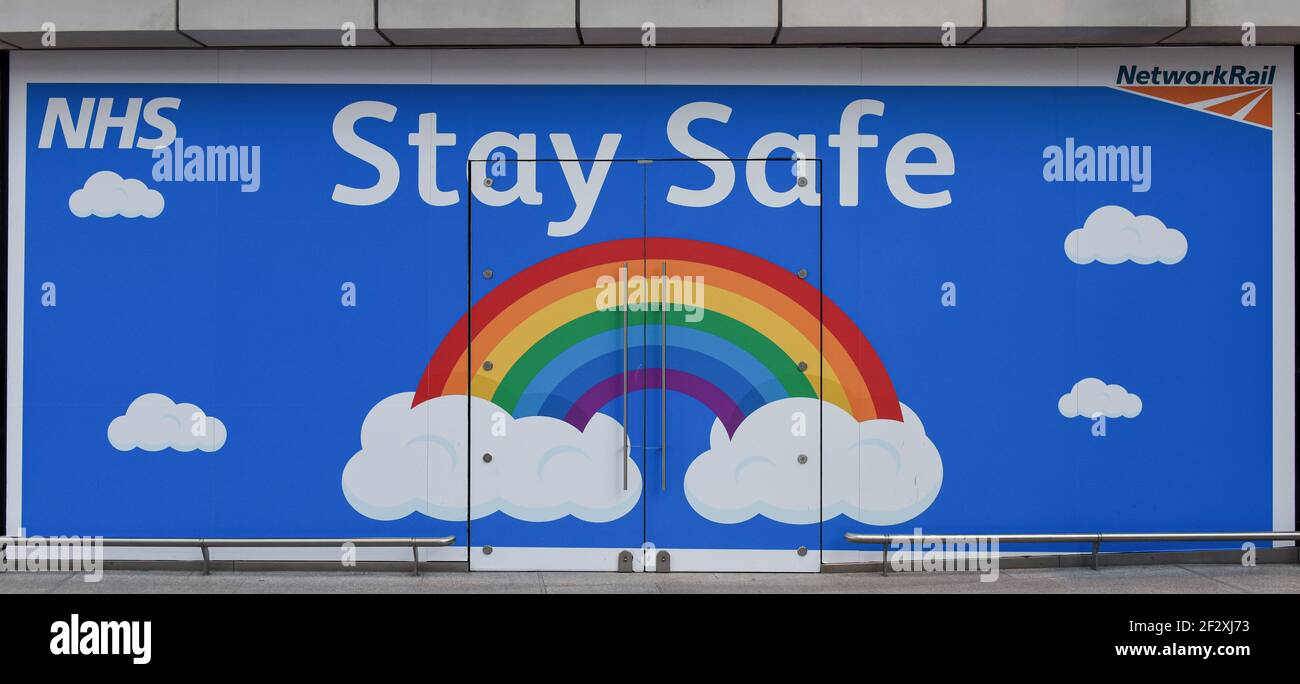 Hall isolé de la gare de London Bridge avec bancs en bois et affiche arc-en-ciel NHS Stay Safe . Banque D'Images