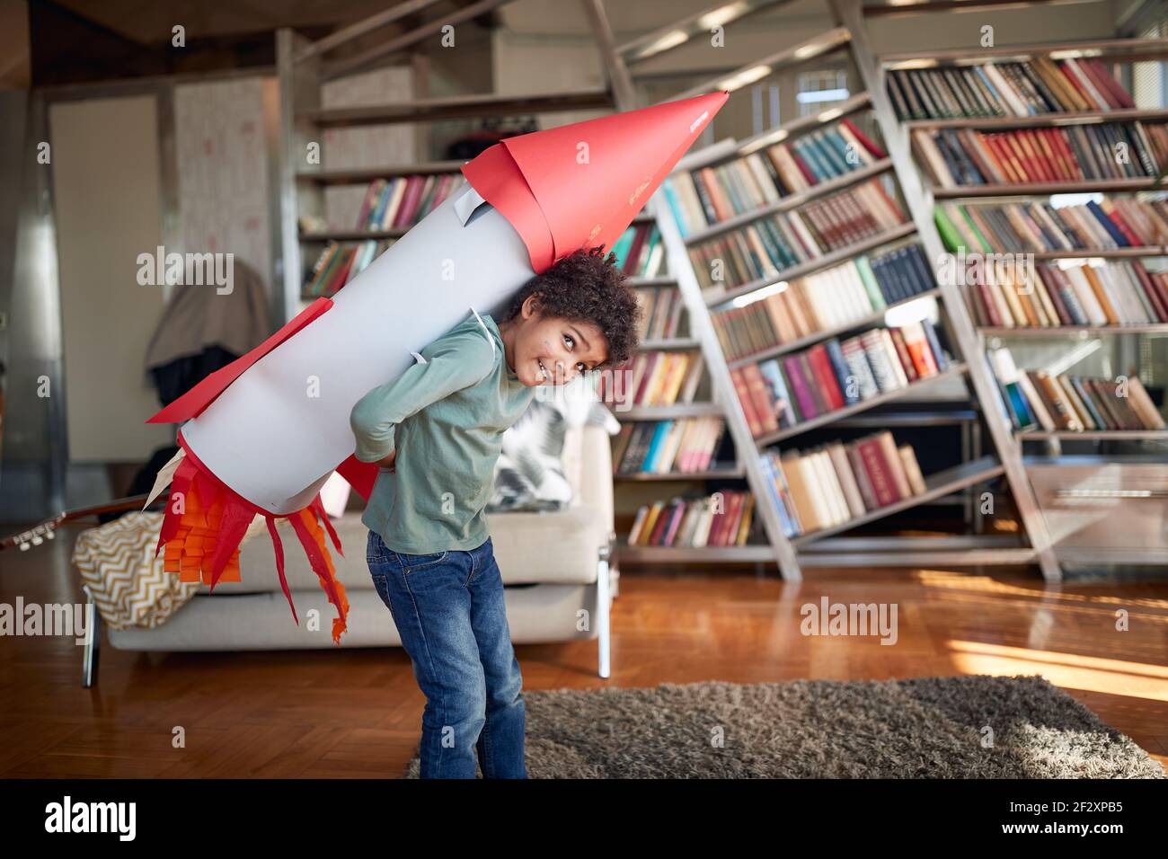 Un petit garçon avec un jouet de fusée sur son dos aime se poser tout en jouant dans une atmosphère détendue à la maison. Maison, jeu, enfance Banque D'Images