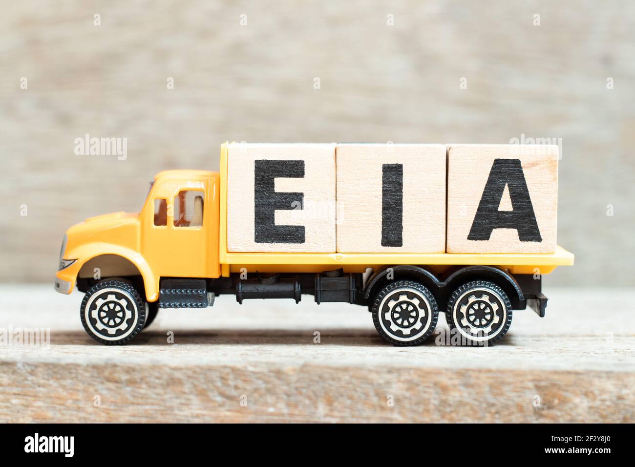 Le camion de jouets tient un bloc alphabétique dans le mot EIA (Abréviation de Environmental impact Assessment) sur fond de bois Banque D'Images