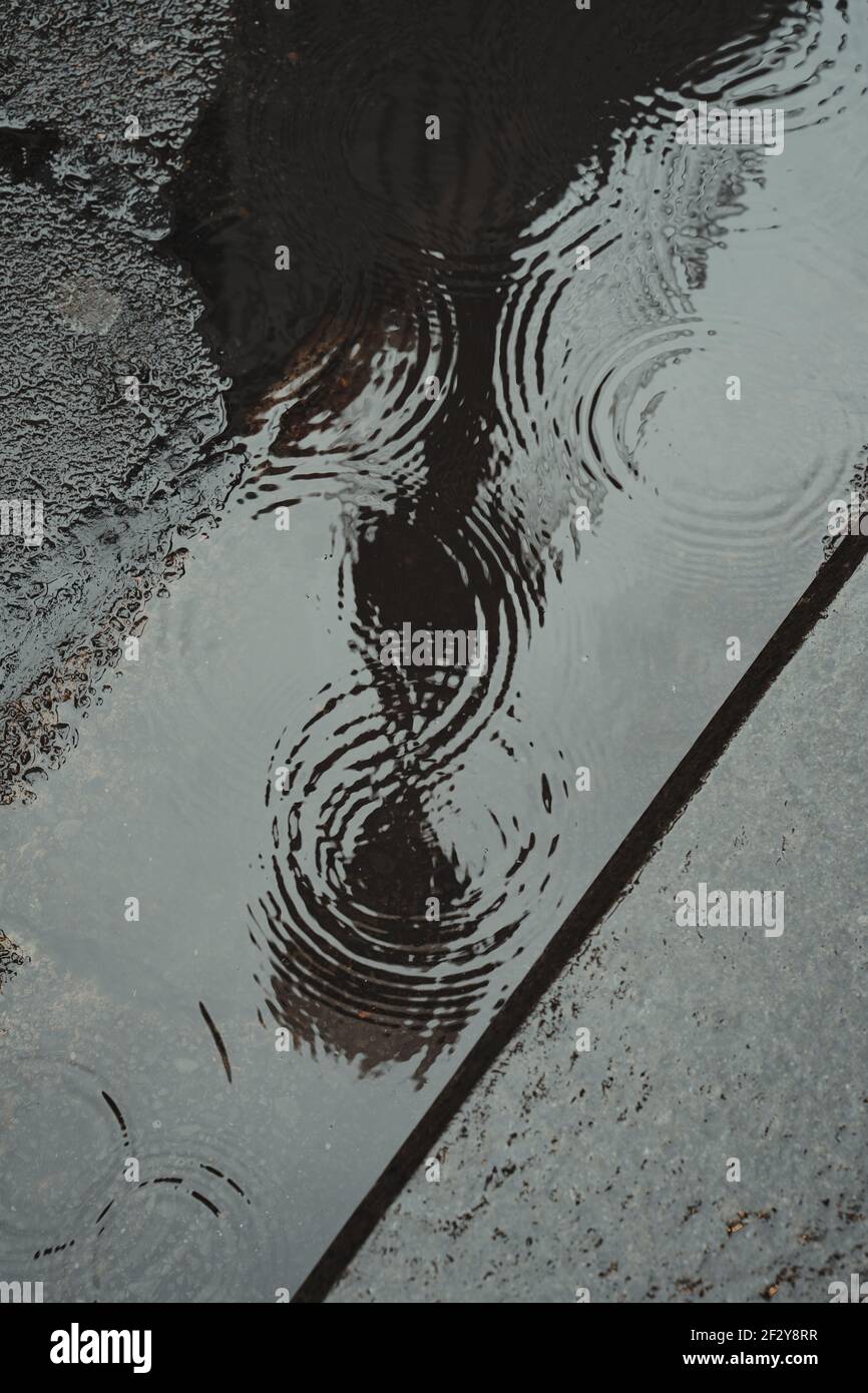 Reflet de bâtiment dans la flaque avec gouttes de pluie Banque D'Images