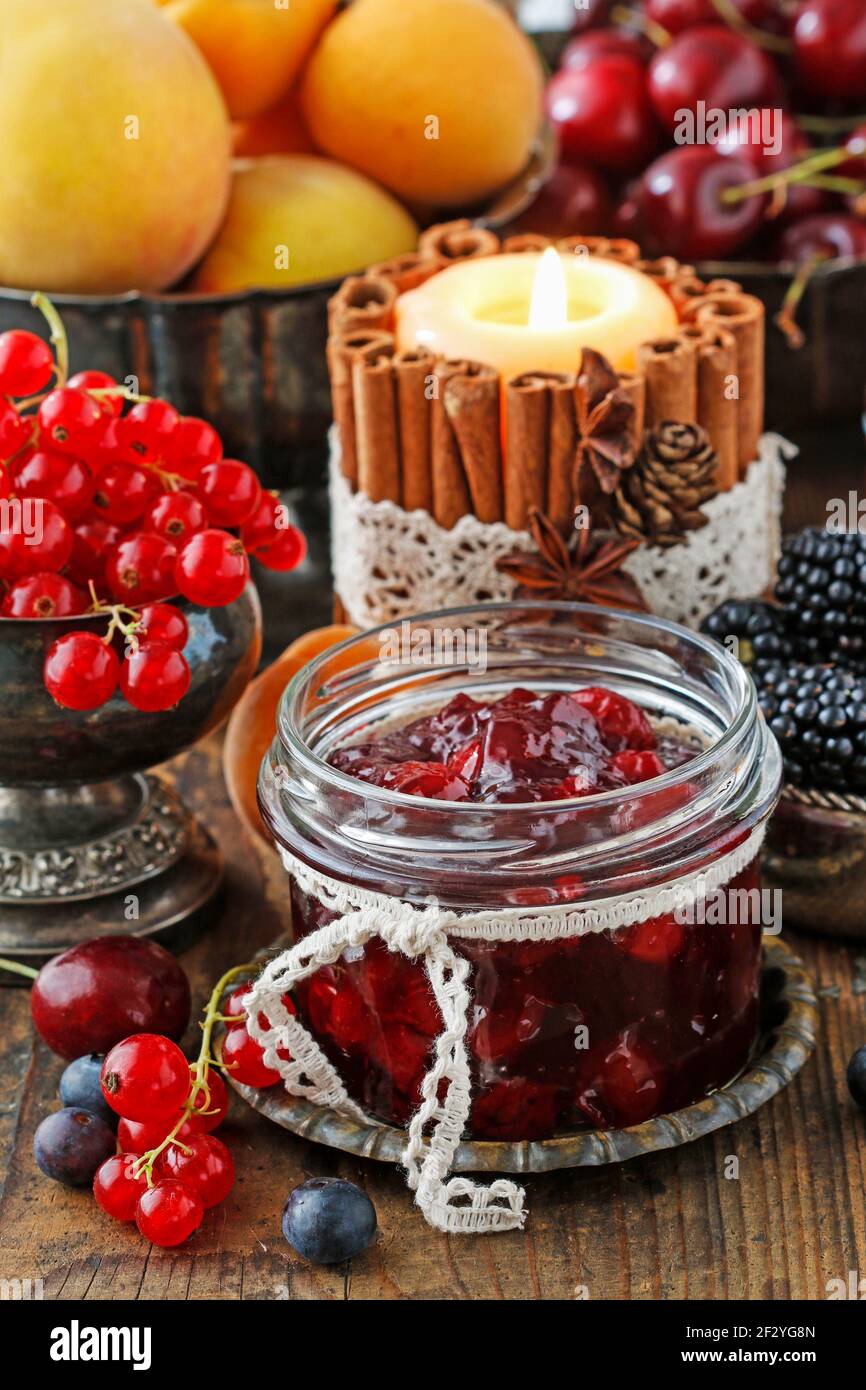 Pots de confiture de fraises de cerise parmi les fruits d'été et d'automne sur une table en bois. Banque D'Images