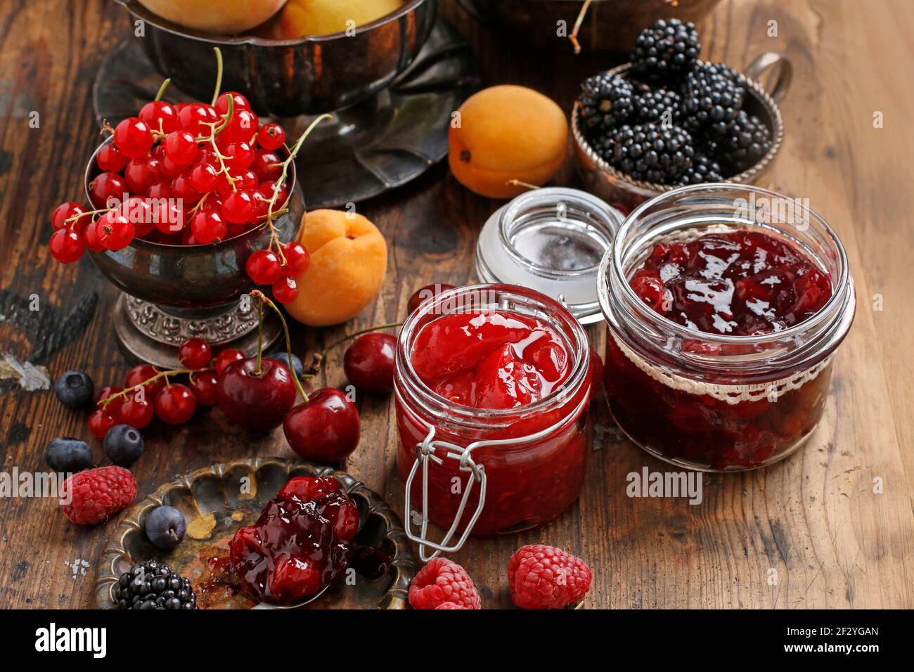 Pots de confiture de fraises de cerise parmi les fruits d'été et d'automne sur une table en bois. Banque D'Images
