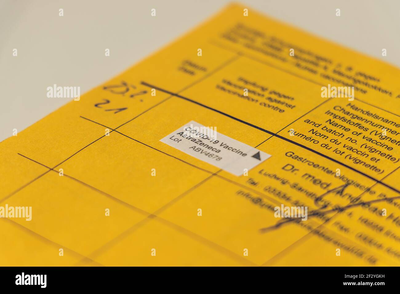 Vue latérale d'une page de la carte de vaccination avec la preuve de la vaccination de Corona AstraZeneca. Ouvrir le certificat de vaccination jaune de l'OMS WIT Banque D'Images