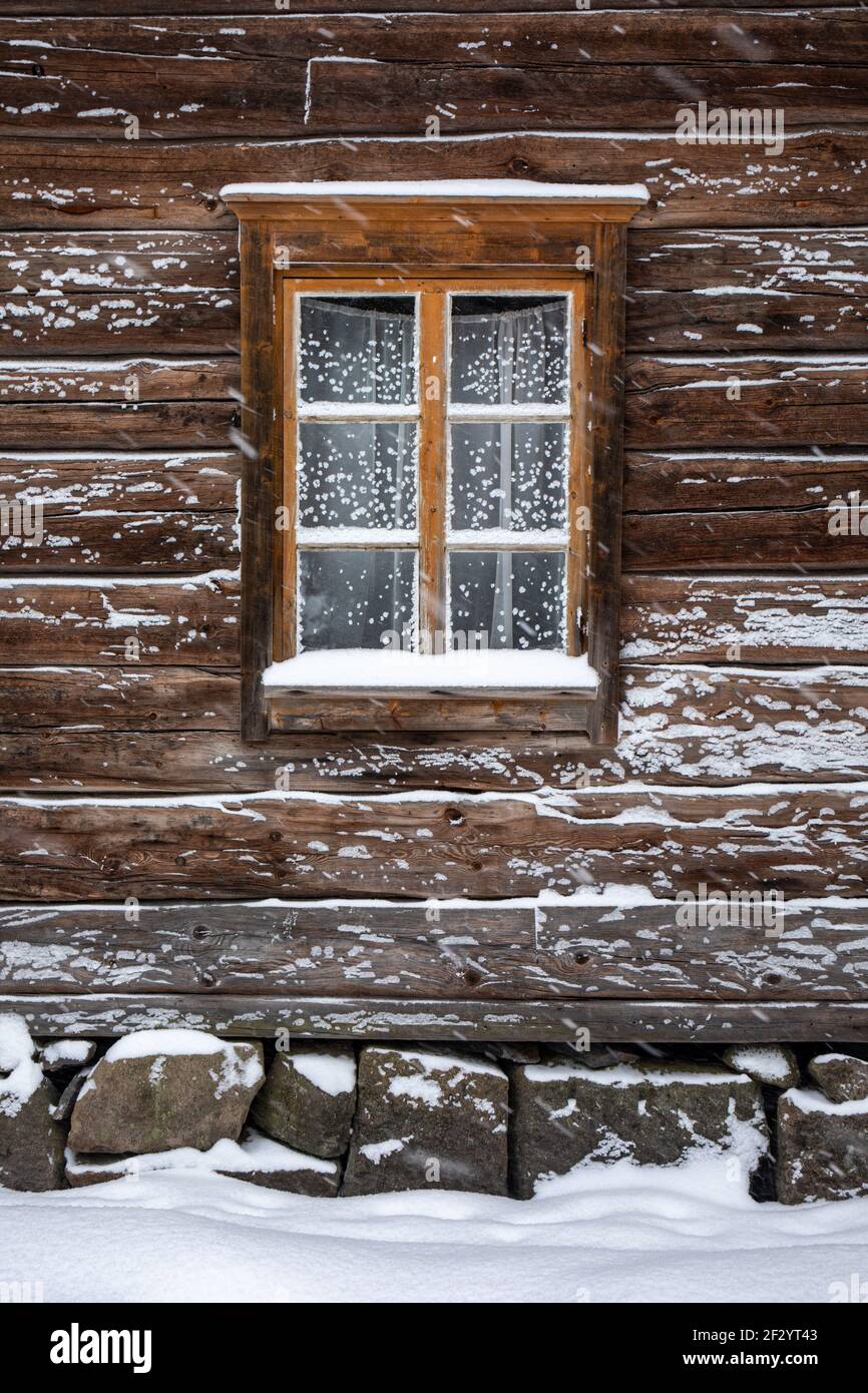 Ancienne fenêtre de bâtiment en rondins avec givre pendant les fortes chutes de neige au Musée en plein air de Seurasaari à Helsinki, Finlande Banque D'Images