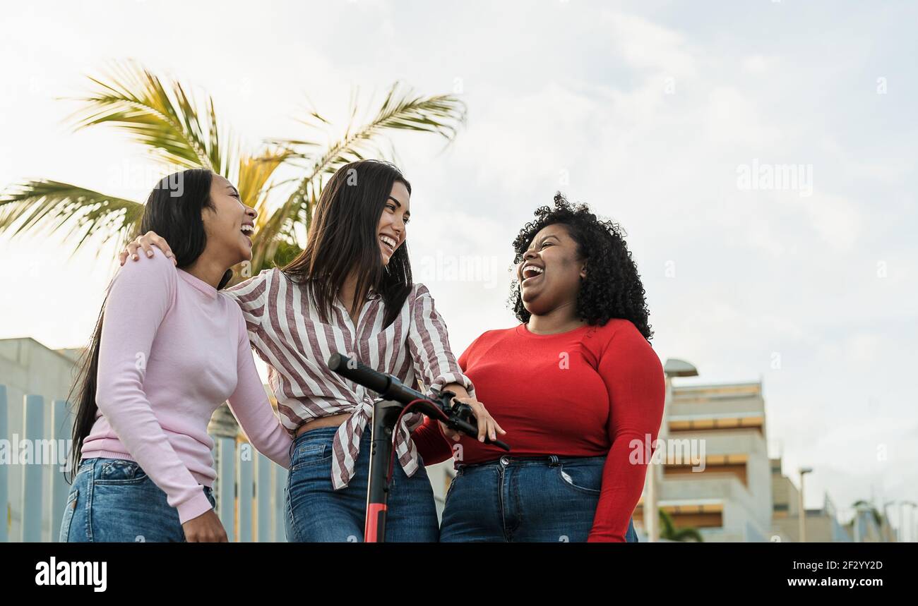 Heureux amis multiraciaux s'amuser avec le scooter électrique dans le ville Banque D'Images