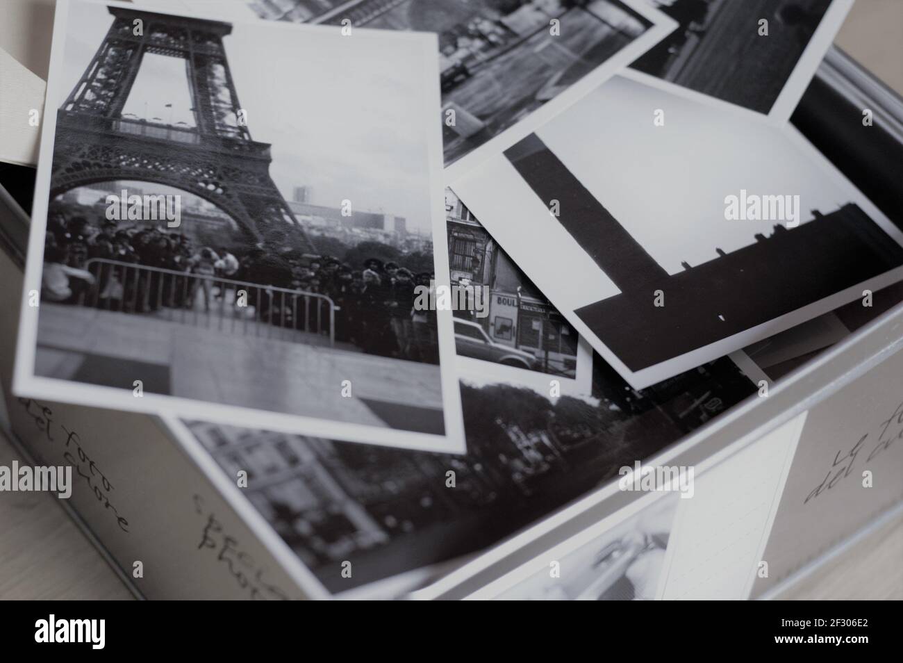 Boîte en métal pleine de photos prises à Paris avec la visite Eiffel en premier plan sur une photo en noir et blanc Banque D'Images