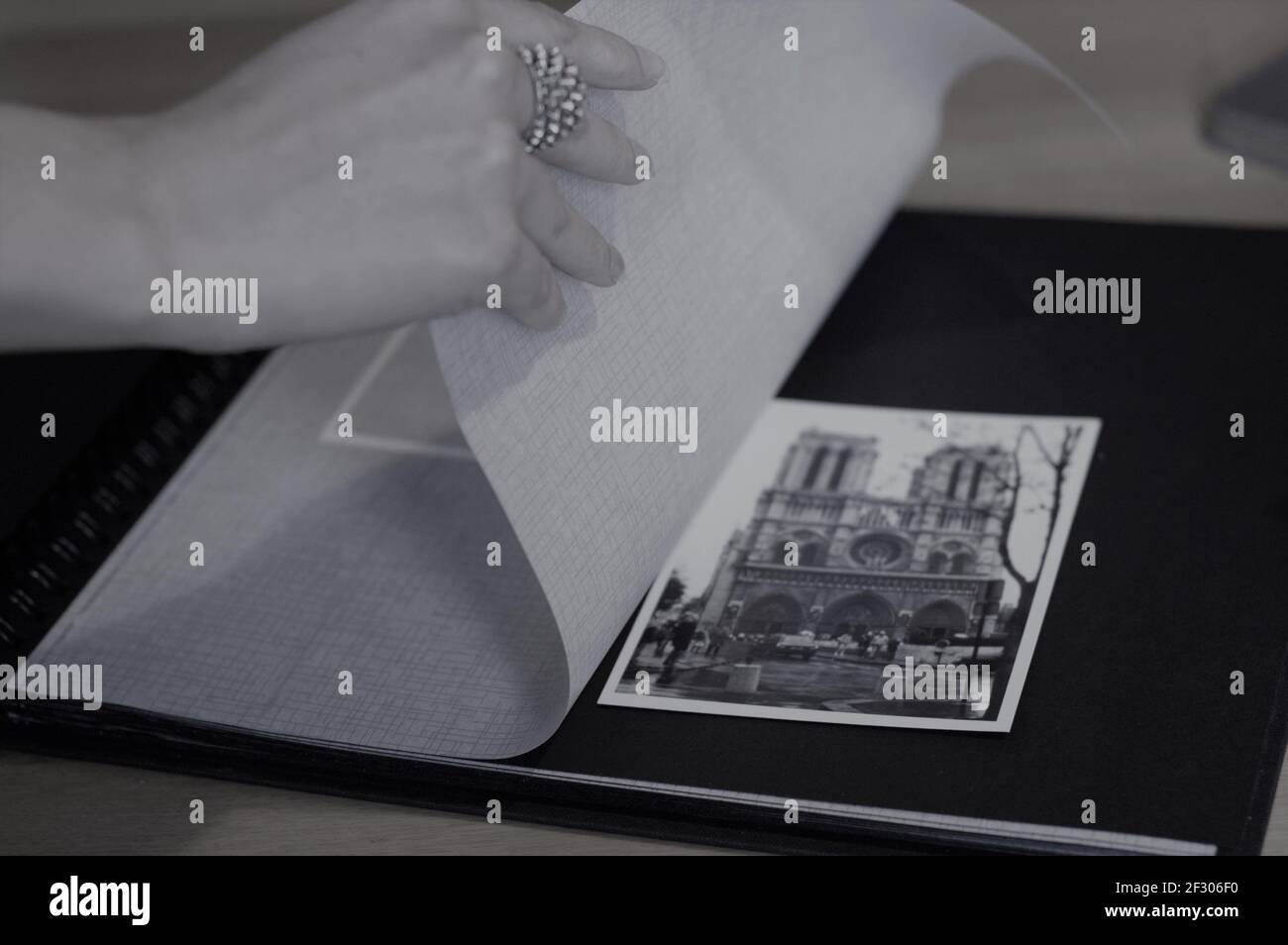 jeune femme main portant un anneau tournant les pages d'un Album photo montrant une photo de l'église notre Dame de Paris photo en noir et blanc Banque D'Images