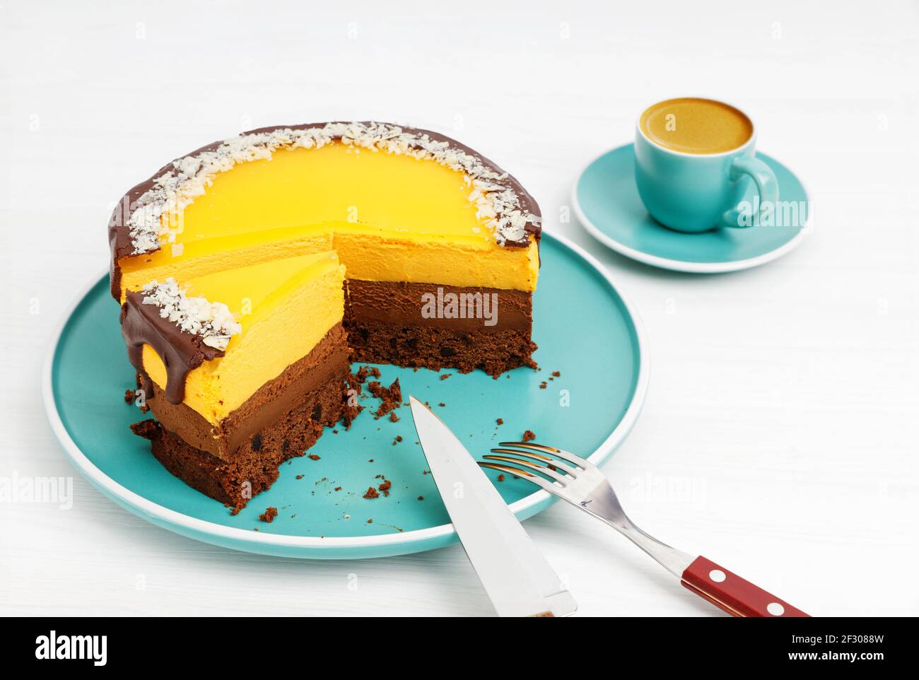 Gâteau au chocolat et à l'orange maison parsemé de tranches d'amande et d'une tasse de café expresso sur une table en bois blanc. Mise au point peu profonde. Banque D'Images Gâteau au chocolat et à l'orange maison parsemé de tranches d'amande et d'une tasse de café expresso sur une table en bois blanc. Mise au point peu profonde. Banque D'Images