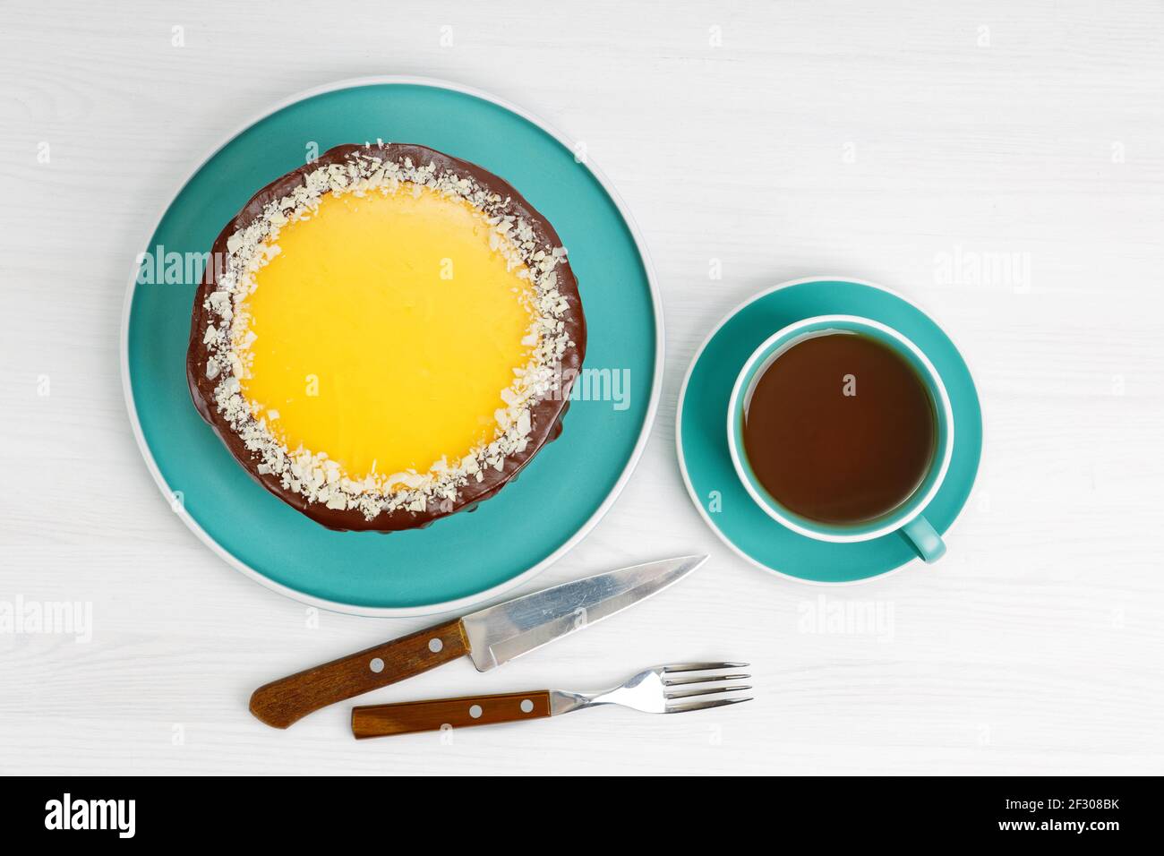 Gâteau au chocolat et à l'orange maison parsemé de tranches d'amande et d'une tasse de thé sur une table en bois blanc. Vue de dessus. Banque D'Images Gâteau au chocolat et à l'orange maison parsemé de tranches d'amande et d'une tasse de thé sur une table en bois blanc. Vue de dessus. Banque D'Images