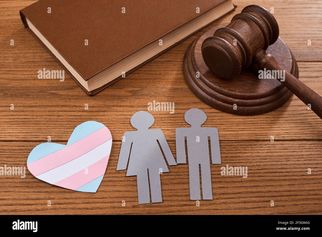 Un coeur en papier avec un drapeau de fierté transgenre, un couple, un gavel de juge et un livre Banque D'Images