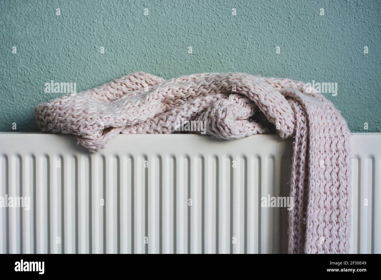 Écharpe tricotée rose douce séchant sur un radiateur de chauffage après avoir été mouillée. Banque D'Images