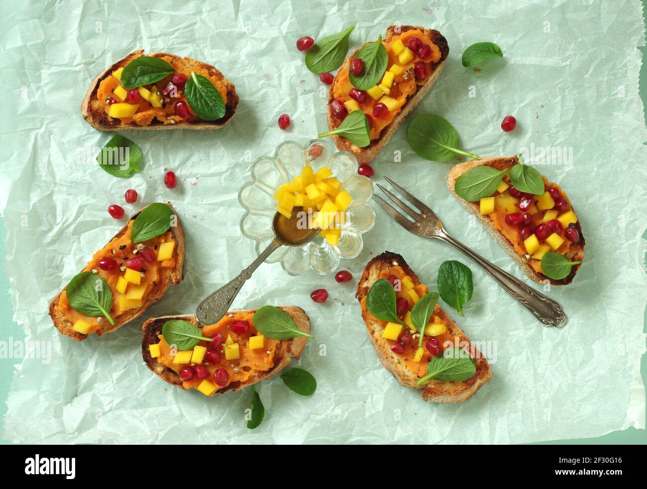 Crostini avec purée de patates douces, mangue, jeunes épinards chinois et grenade Banque D'Images