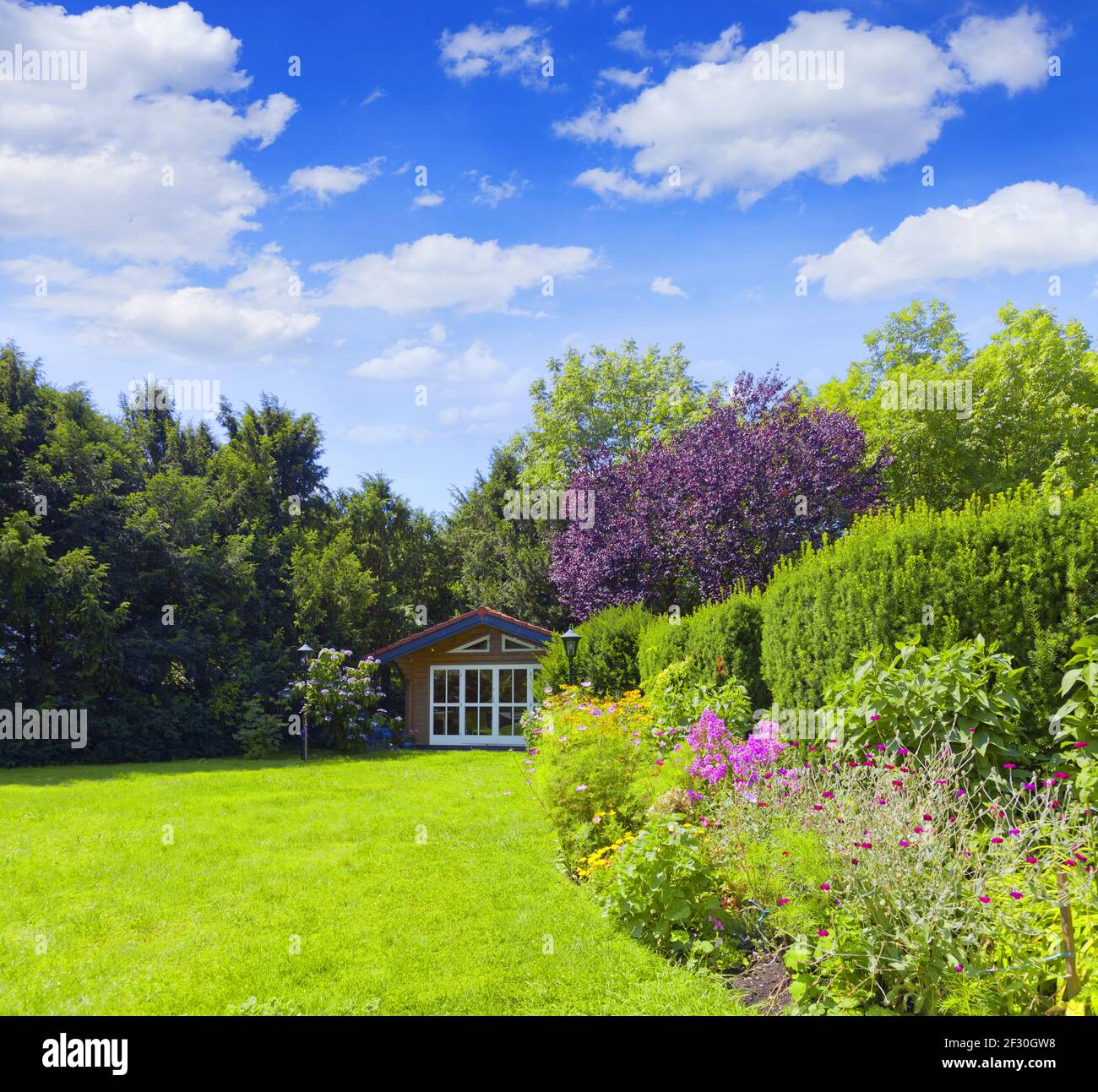 Jardin bien entretenu avec un lit de fleur coloré et un abri de jardin Banque D'Images