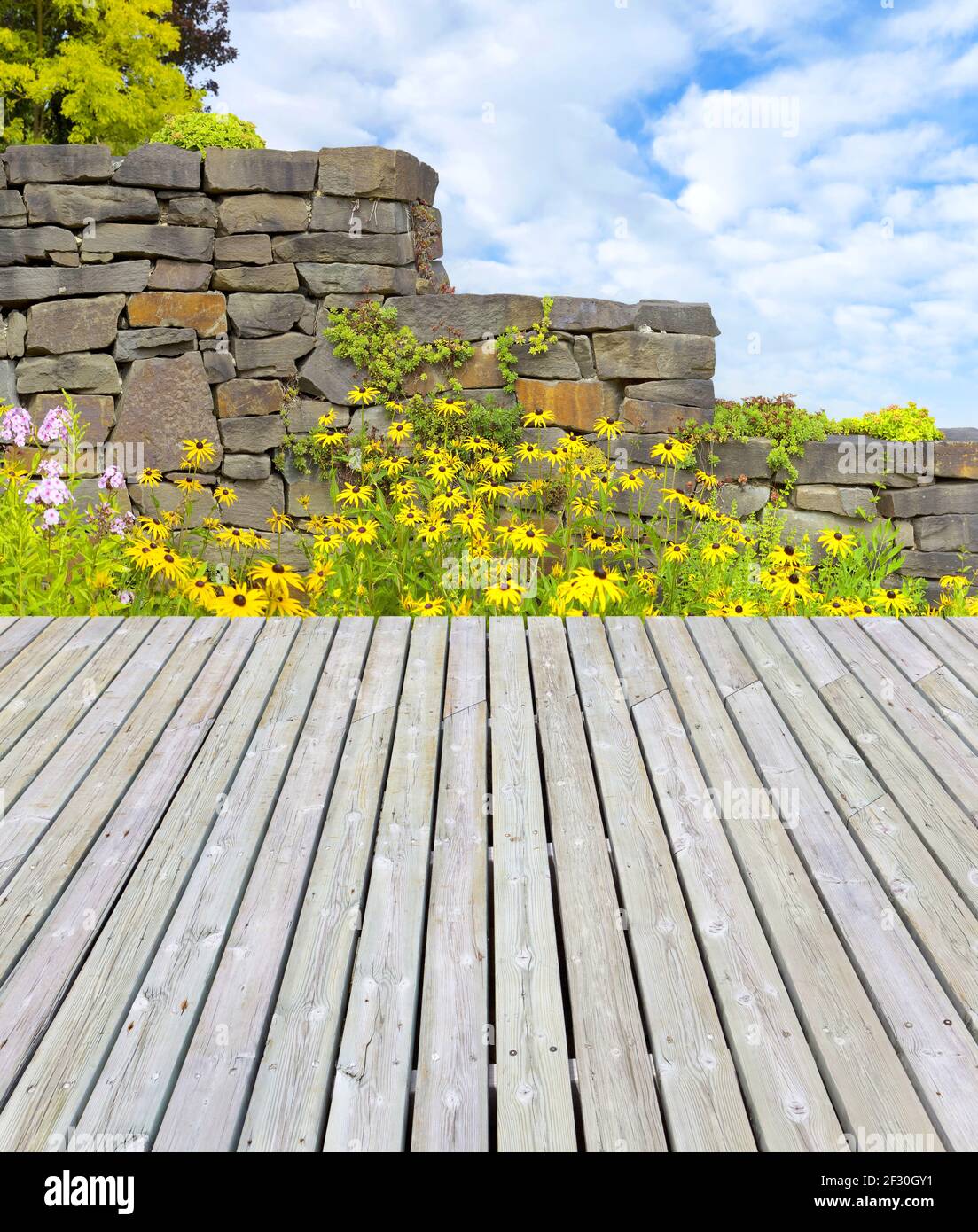 Belle terrasse bien entretenue avec un lit de fleurs coloré et un mur de jardin Banque D'Images