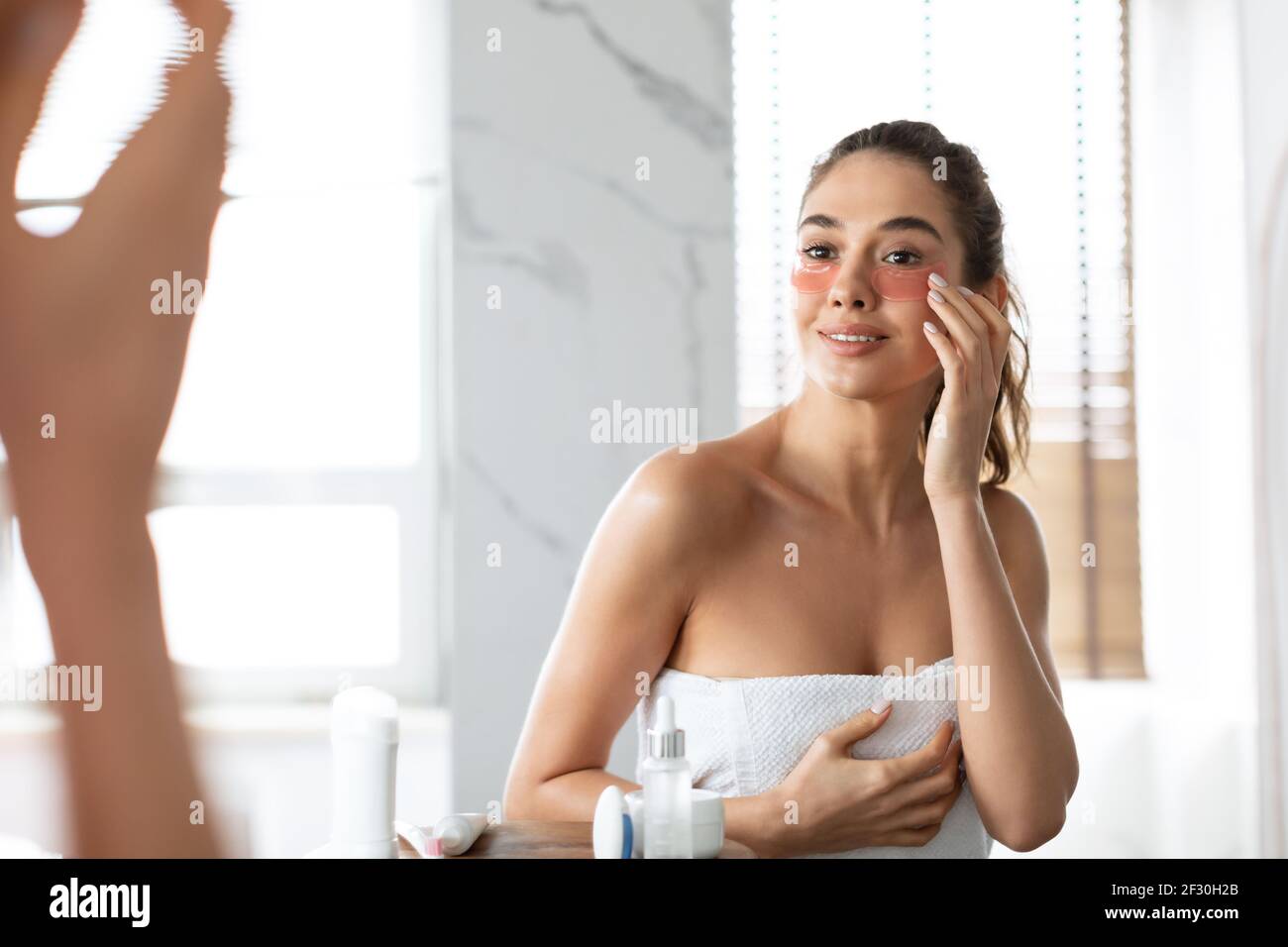 Femme appliquant des taches sous les yeux peau hydratante sous les yeux dans la salle de bains Banque D'Images