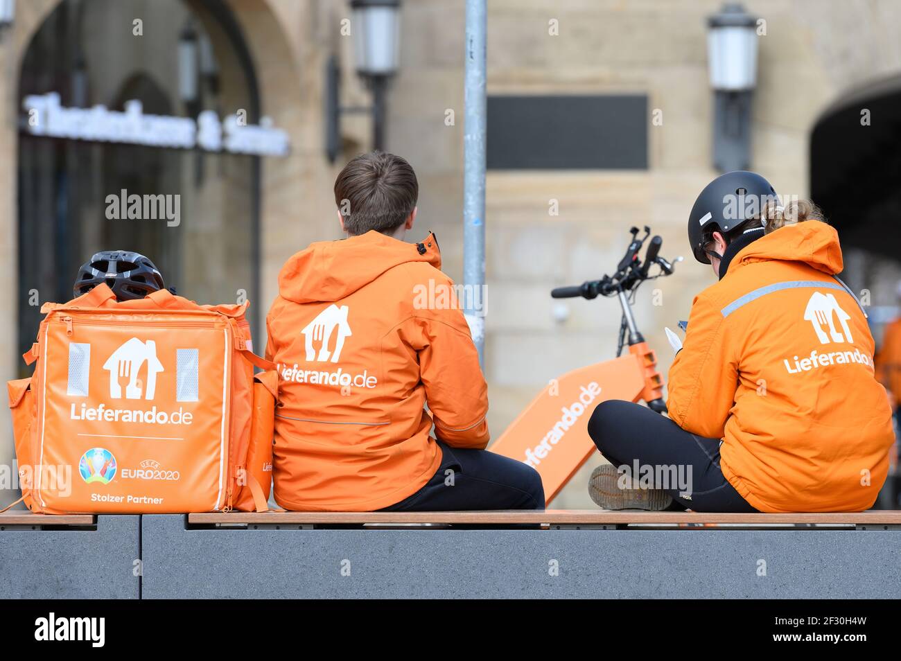 Dresde, Allemagne. 13 mars 2021. Deux coursiers de vélo du service de livraison Lieferando s'assoient à côté d'un sac à dos sur Post Square. Credit: Sebastian Kahnert/dpa-Zentralbild/dpa/Alay Live News Banque D'Images