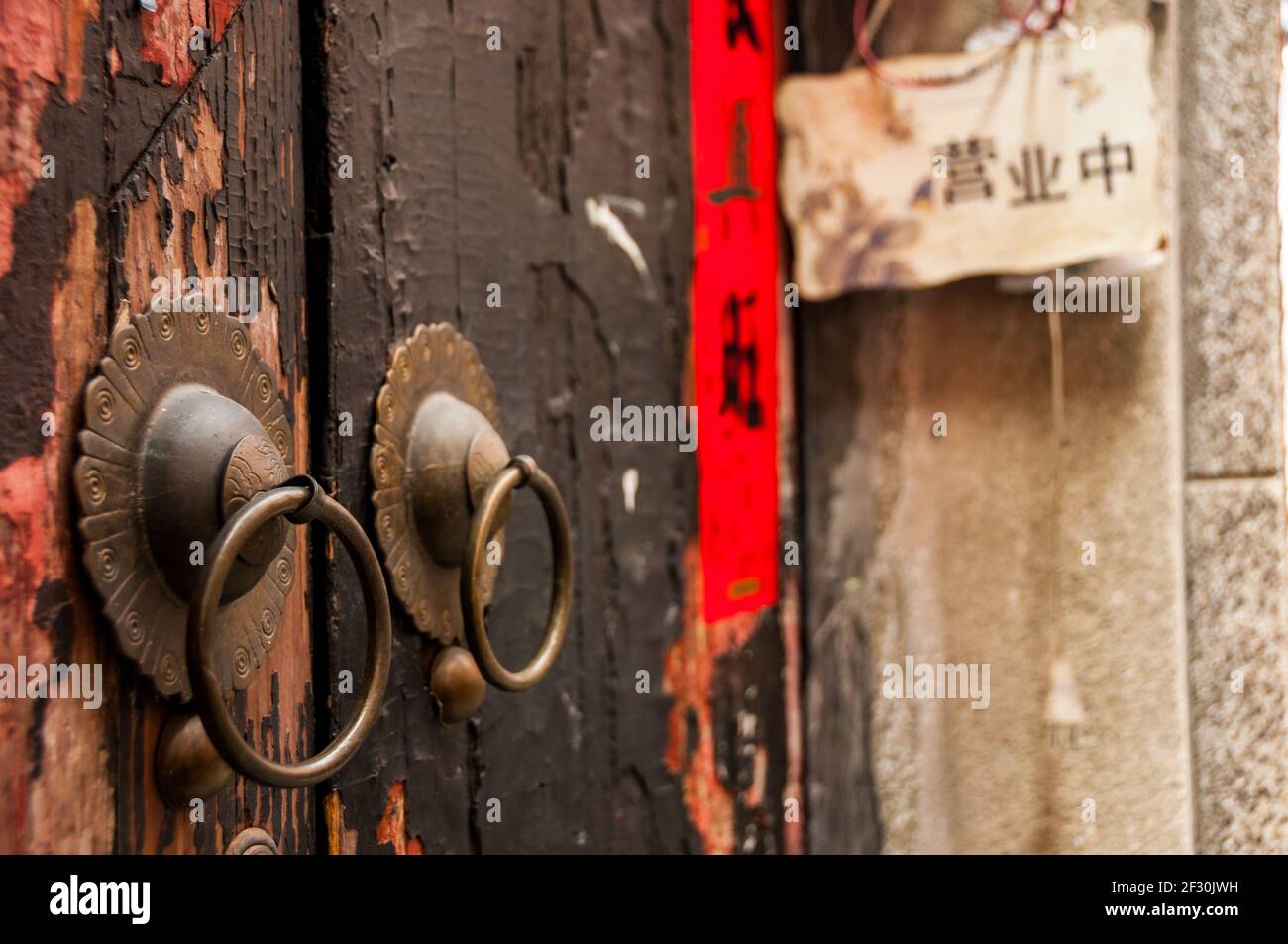 Poignées de porte traditionnelles en laiton sur une porte avec peinture écaillée dans Tianzifang de Shanghai. Huangpu District, Shanghai, Chine, Asie. Banque D'Images