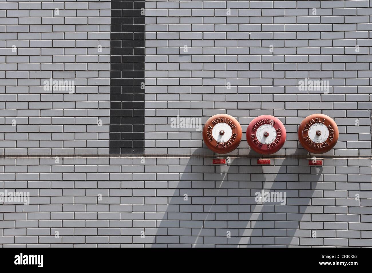 Gros plan de trois alarmes rouges de gicleurs d'incendie montées sur un mur en briques grises Banque D'Images