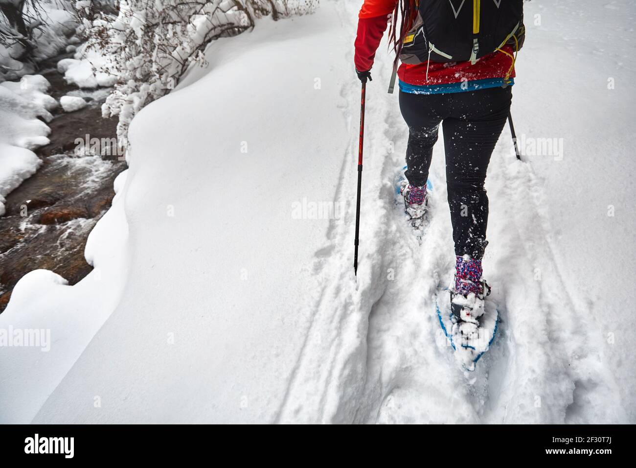 Femme portant des chaussures d'exposition marche dans la forêt enneigée d'hiver près de la rivière à Almaty, Kazakhstan Banque D'Images