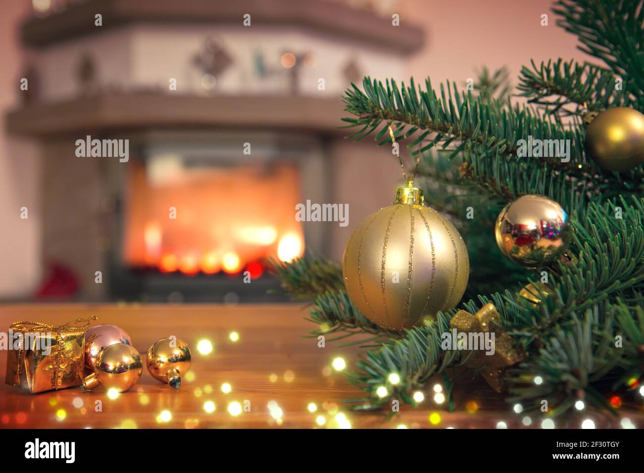 Arrière-plan de Noël avec boule dorée, cheminée et branche de sapin décorée. Banque D'Images