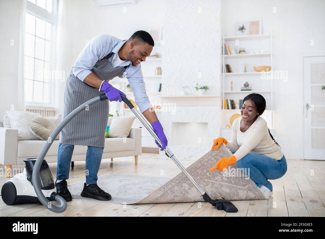 Positif noir couple de nettoyage ensemble, passer l'aspirateur sous la  moquette à leur maison, l'espace de copie Photo Stock - Alamy