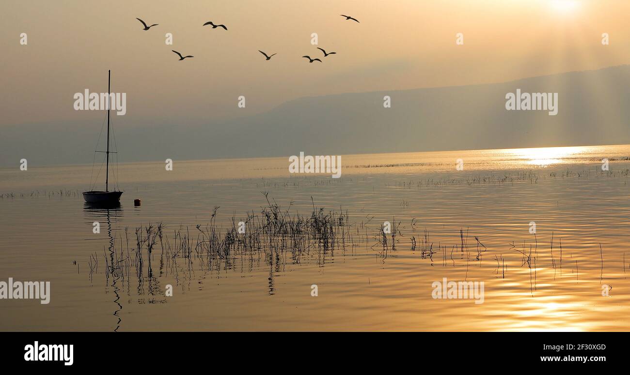 Lever du soleil sur le lac. Bateau flottant sur l'eau calme sous un coucher de soleil étonnant. Banque D'Images