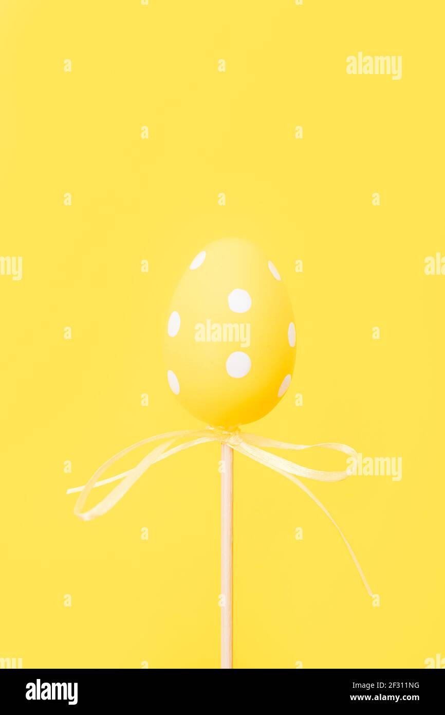 Œuf de Pâques jaune sur bâton sur fond jaune. Carte de vœux de Pâques avec espace pour copier. Banque D'Images