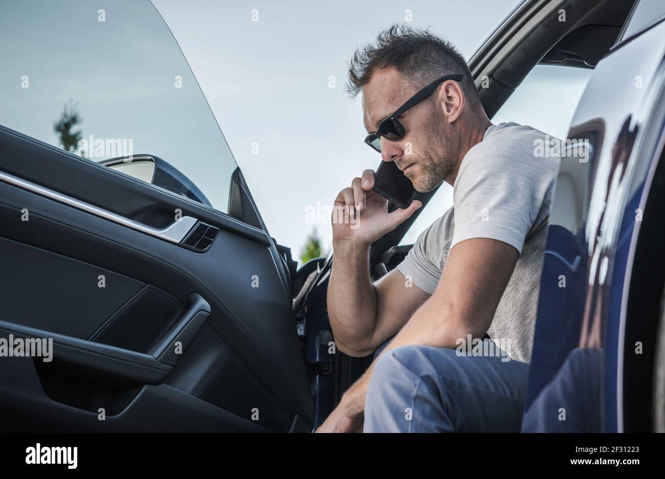 Chauffeur de race blanche dans ses 40 ans effectuant un appel d'urgence à partir de sa voiture. Appel de l'assistance routière. Thème de l'industrie du transport. Banque D'Images