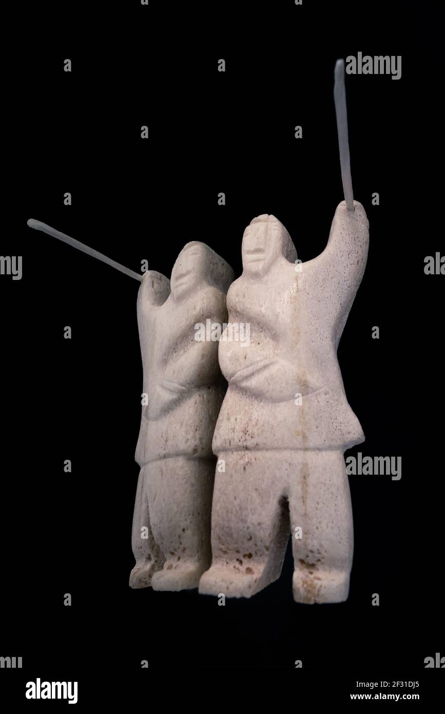 Petite statue de chasseur inuit avec une lance en os animal. Isolé sur fond noir. Art inuit. Culture tribale des indigènes dans le nord Banque D'Images