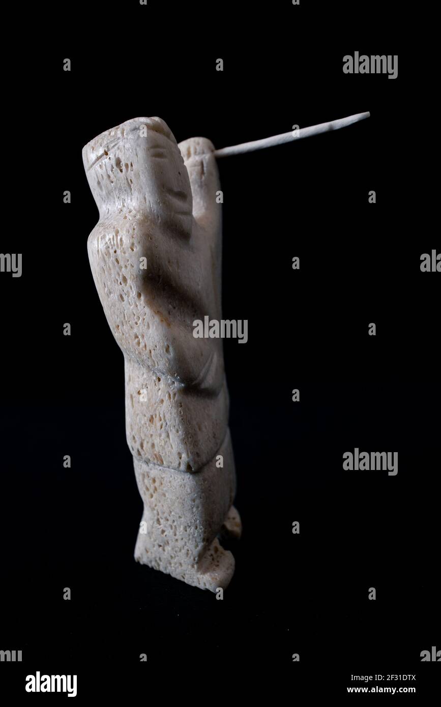 Petite statue de chasseur inuit avec une lance en os animal. Isolé sur fond noir. Art inuit. Culture tribale des indigènes dans le nord Banque D'Images