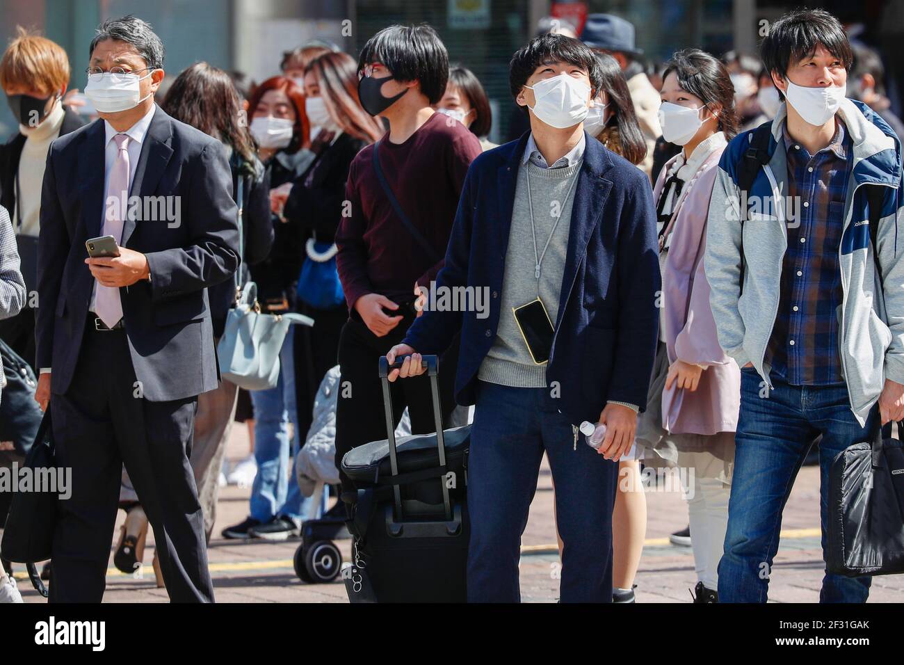 Les personnes portant des masques de visage comme mesure préventive contre la propagation de covid-19 traversent la célèbre intersection de broussaires près de la station de Shibuya. Le gouvernement japonais s'est penché vers la fin de l'état d'urgence pour Tokyo et les régions environnantes au-dessus de COVID-19 comme prévu le 21 mars, a rapporté le journal dimanche. Banque D'Images