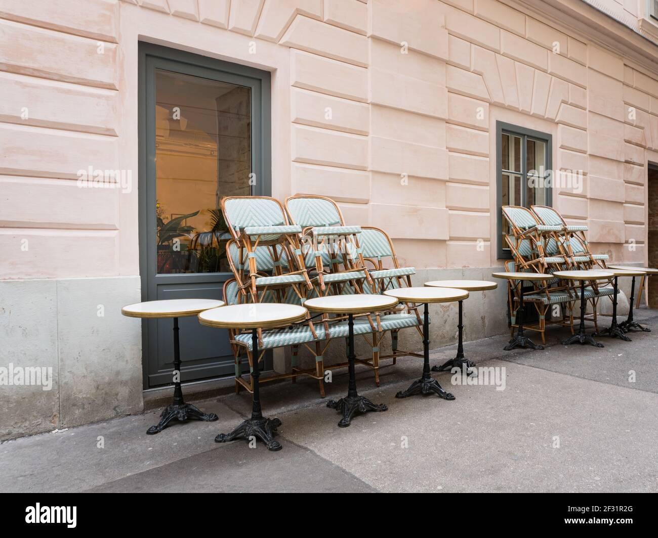 Chaises et tabourets empilés sur des tables devant un café de restaurant fermé vide pendant la pandémie Covid-19 Corona. Banque D'Images