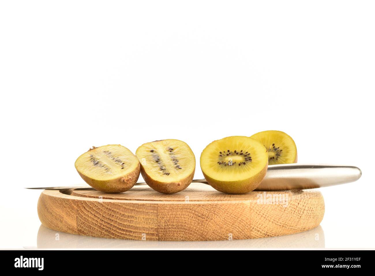 Quatre moitiés de kiwi doré doux et savoureux bio mûr, sur un plateau en bois rond avec un couteau en métal, en coupe longitudinale et transversale, sur un backgrou blanc Banque D'Images