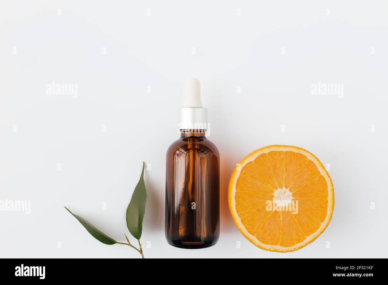 Huile essentielle d'orange en flacon de verre avec feuille verte. Concept cosmétique sur fond blanc, pose plate isolée. Photo de haute qualité Banque D'Images