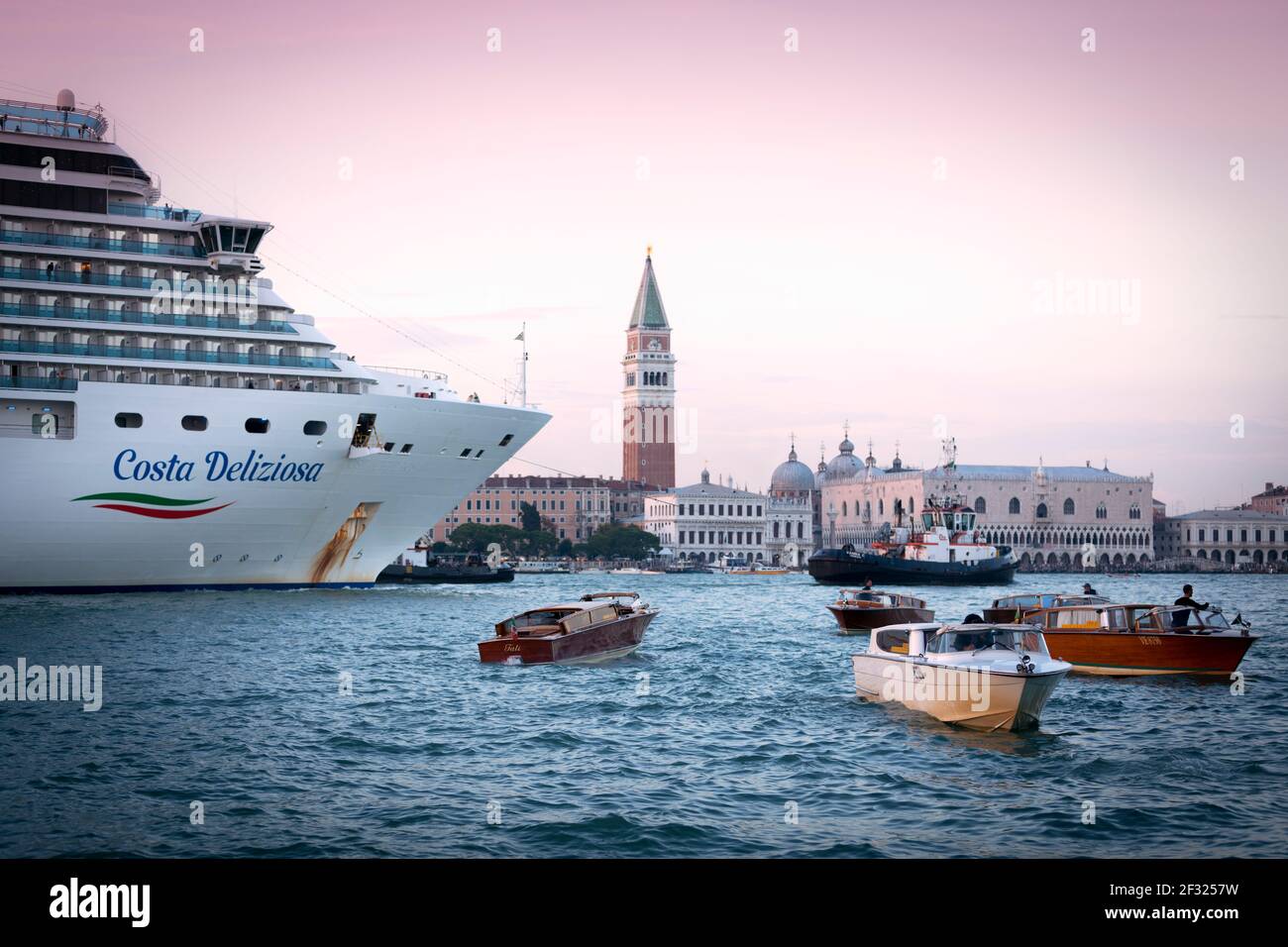 Italie, Venise, un bateau de croisière sur la Canale di San Marco, avec des bateaux-taxis au premier plan. Banque D'Images