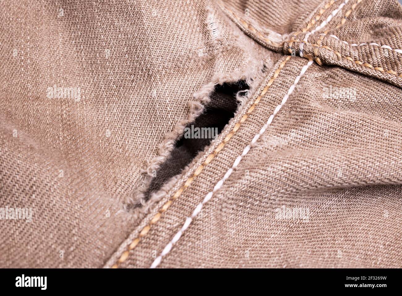 Trou dans le denim gris gros plan, arrière-plan ou texture Banque D'Images