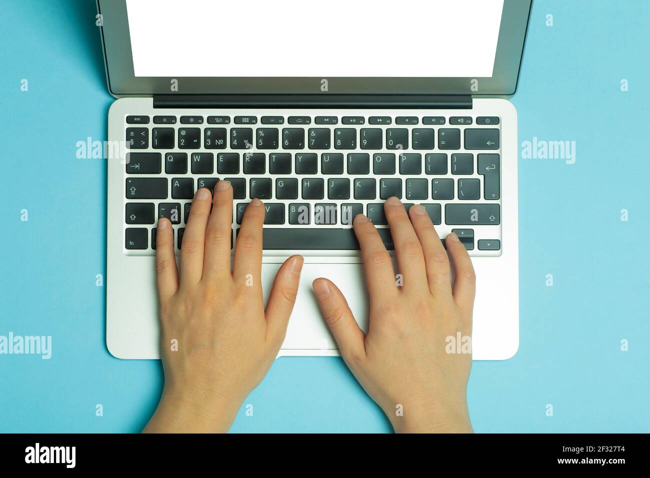 Les mains des femmes derrière un ordinateur portable. Les mains des femmes  travaillent sur un clavier d'ordinateur sur Internet sur un fond bleu du  lieu de travail. Photo de haute qualité Photo
