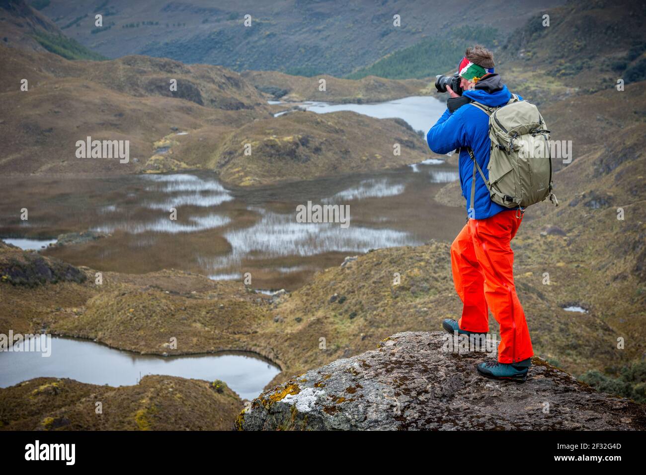 Un jeune homme sur un point de vue qui photographie la beauté de la nature dans le parc national de cajas près de Cuenca, Equateur avec vue panoramique sur les lacs, les ruisseaux, la vallée Banque D'Images